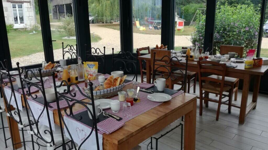 A breakfast setup with a table set for two, including bread, butter, and beverages.