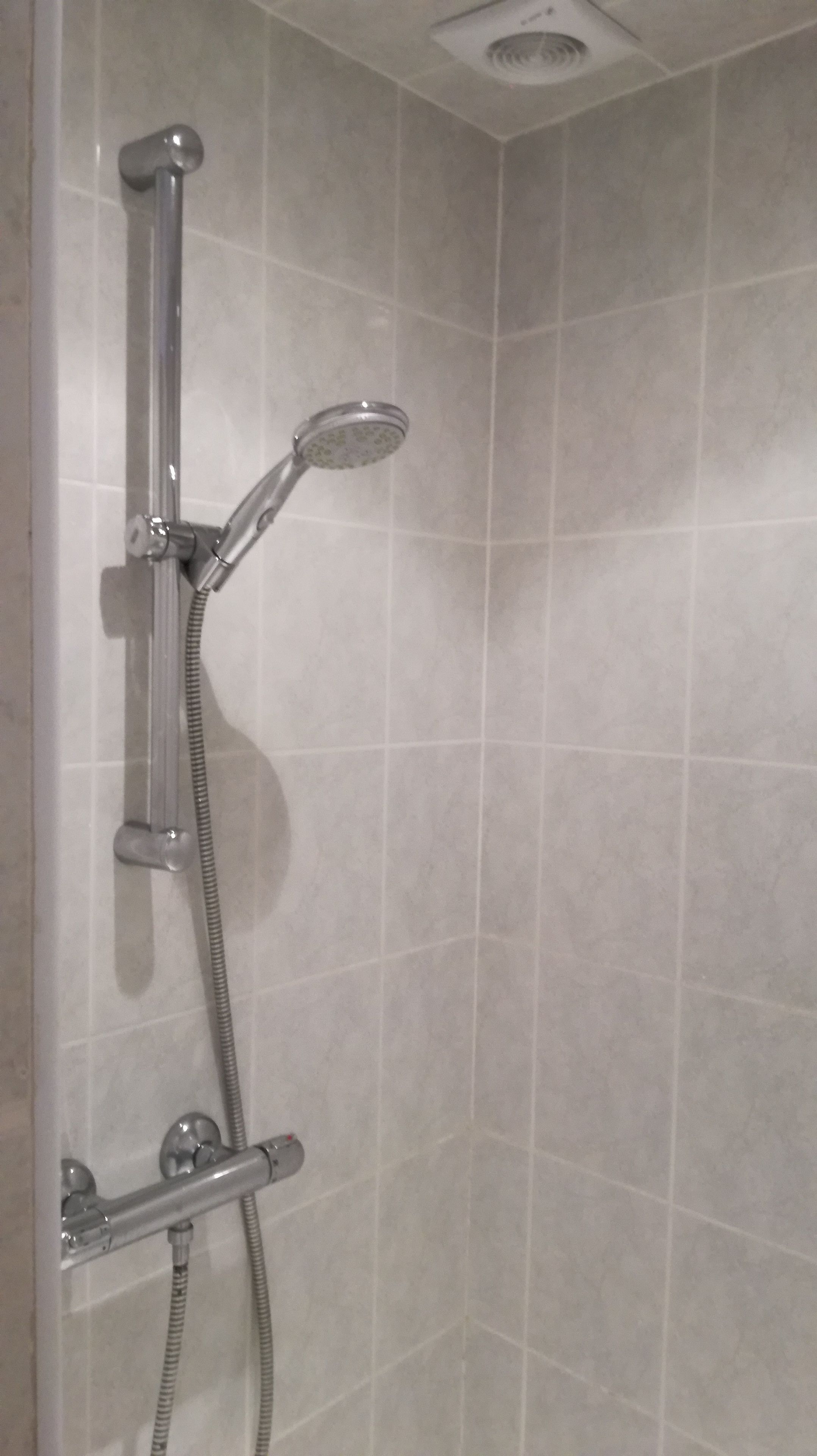 A shower with a handheld showerhead and a handheld hose.