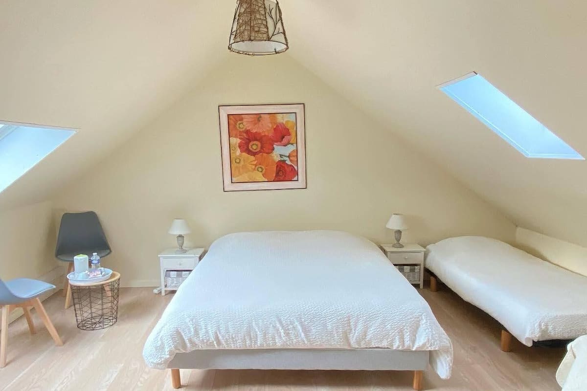 Ein Schlafzimmer mit einem großen Bett, zwei Nachttischen, einem Sessel und einem Bild an der Wand.
