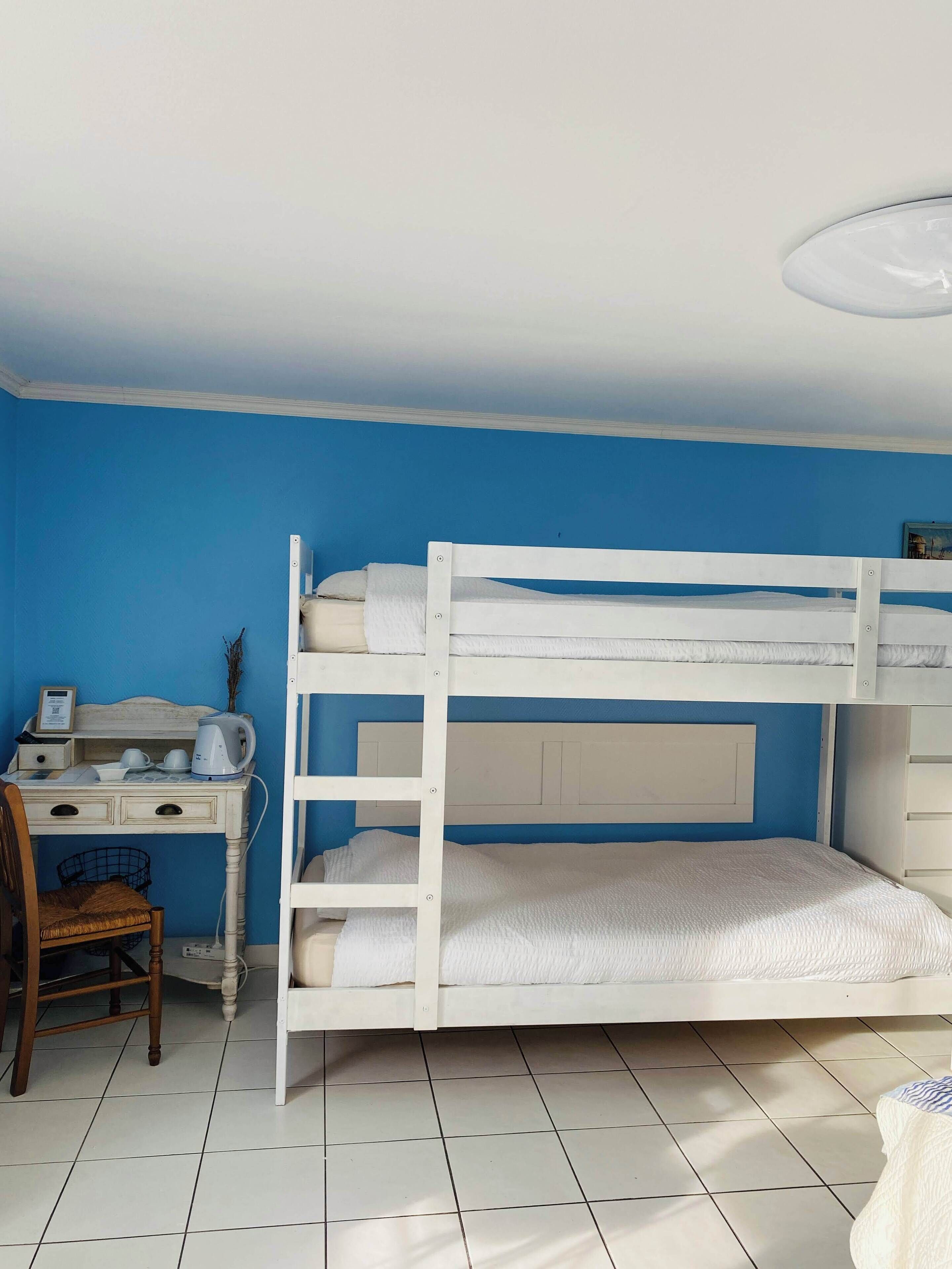 Una cama litera en una habitación con paredes azules y suelo blanco.