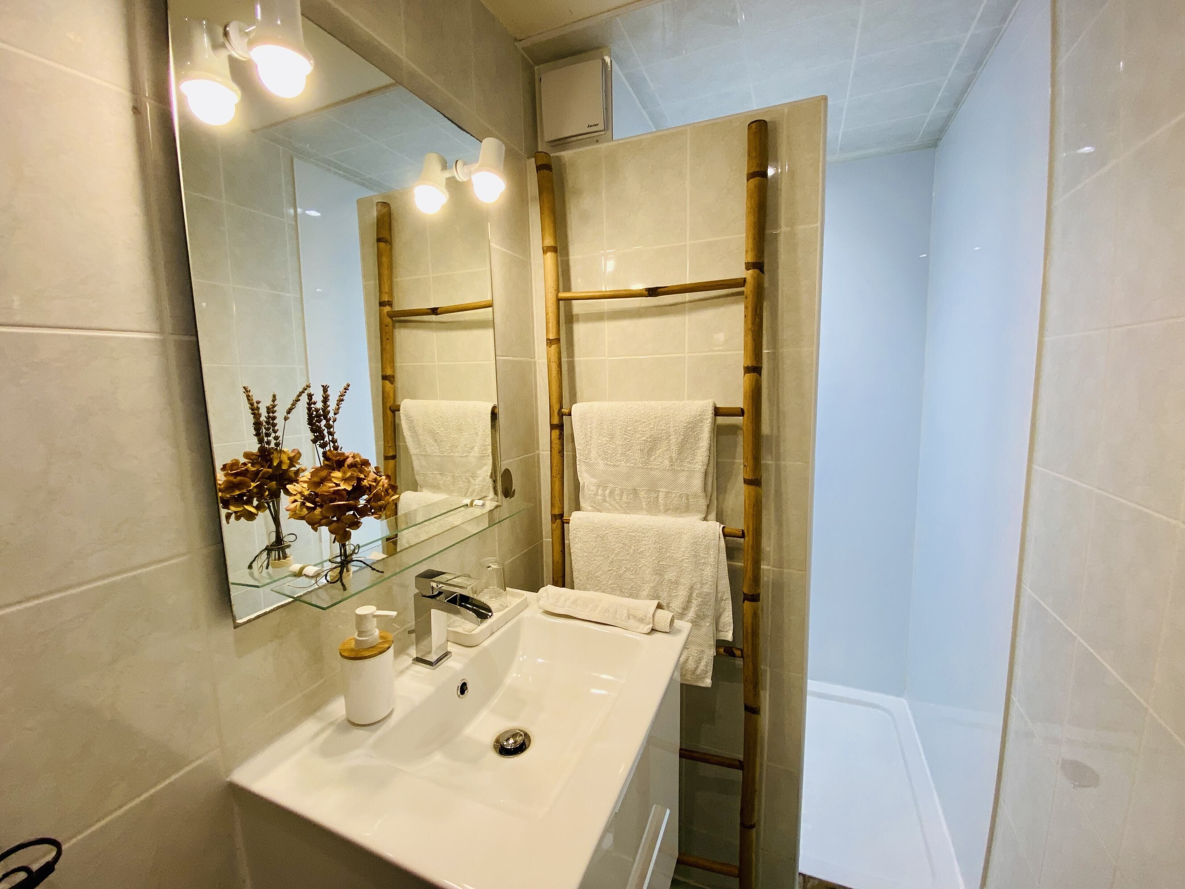 Een badkamer met een wit wastafelmeubel, een spiegel en een handdoekhouder.