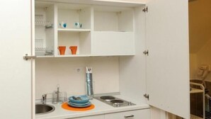 Eine kleine Küche mit Spüle, Herd und Regalen zur Aufbewahrung.