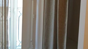 Ein Zimmer mit einer Schiebetür zum Balkon, einem Kleiderschrank und einem teilweise sichtbaren Bett.