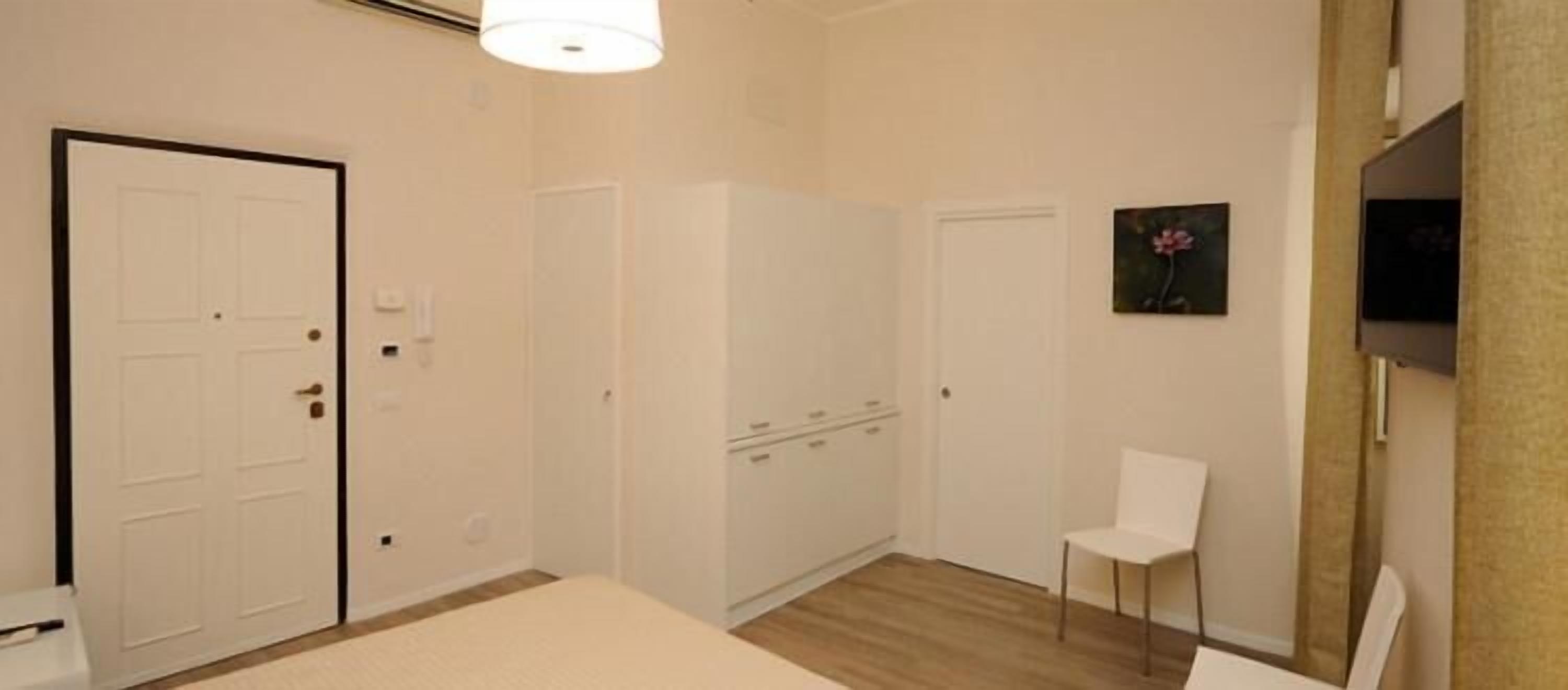 Een kamer met een witte deur, een witte stoel en een witte kast.
