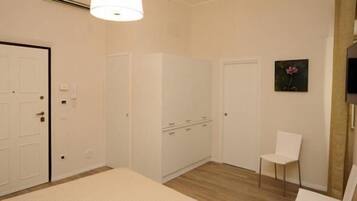 Een kamer met een witte deur, een witte stoel en een witte kast.