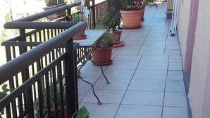 A balcony with potted plants, a metal railing, and a tiled floor. - Auberge du coteau (Saint-Affrique)