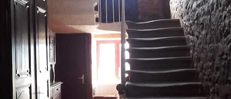 A staircase leading to a higher floor, a wooden cabinet, and a door with a window.