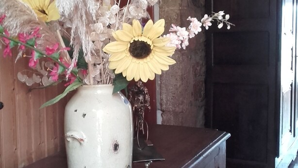 A wooden cabinet with a white vase containing dried flowers and a sunflower. - Auberge du coteau (Saint-Affrique)