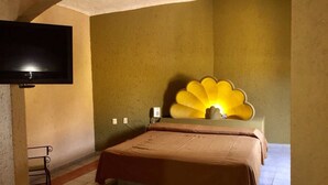 A room with a bed, a television mounted on the wall, and a unique shell-shaped light fixture. - El Fuerte Motel (Acapulco)