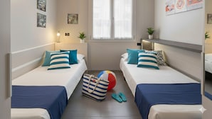 A hotel room with two single beds, a large window with sheer curtains, a small table with a lamp, and wall art. - Da Bruno (Imperia)