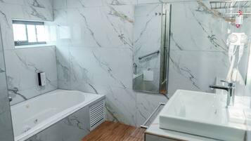 A modern bathroom with a marble wall, a bathtub, a shower, and a sink.