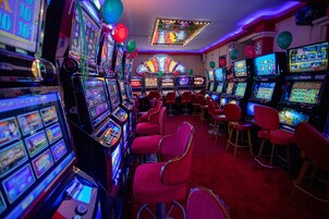 A casino with multiple slot machines and red bar stools.