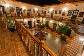 Un patio de varios niveles con escalera de madera, asientos al aire libre y banderas.