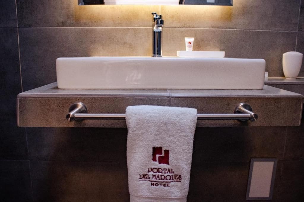 Une salle de bain avec un lavabo blanc, un porte-serviettes avec une serviette et un miroir au-dessus du lavabo.