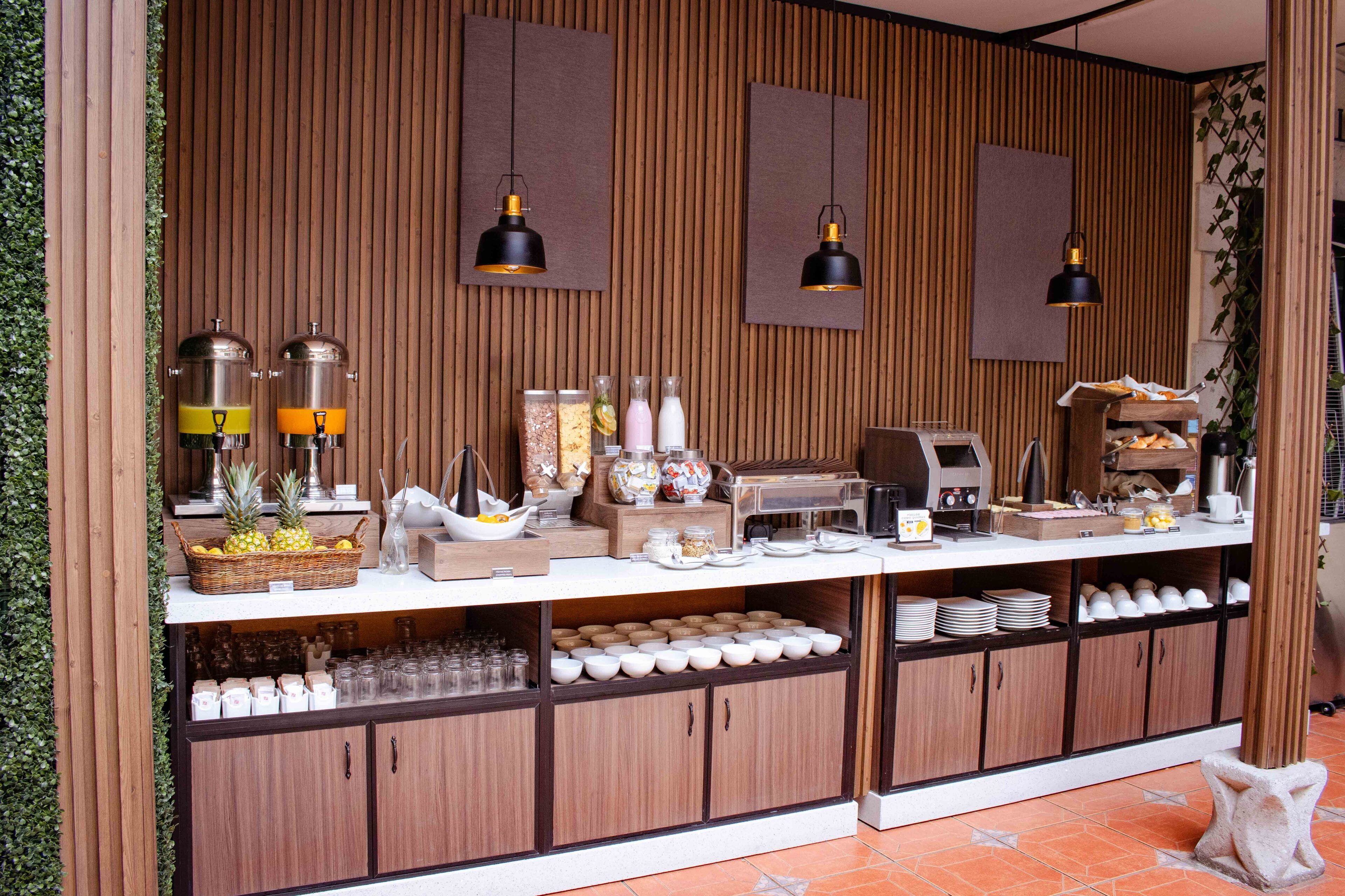 Un buffet de petit-déjeuner proposant une variété d’aliments et de boissons, notamment des fruits, des boissons diverses et une machine à café.