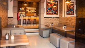 Un restaurante acogedor con barra, asientos con cojines y obras de arte en las paredes.