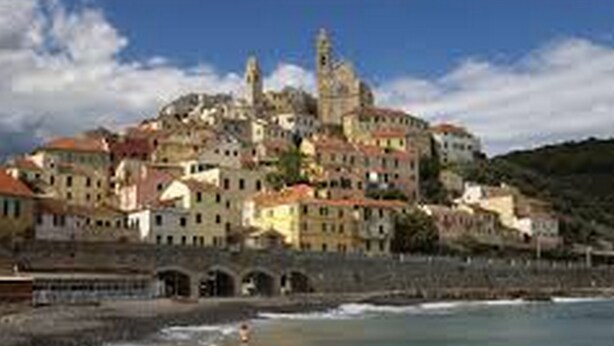 A coastal town with historic buildings, a prominent church, and a beach in the foreground. - Da Simona Appartamenti (Imperia)