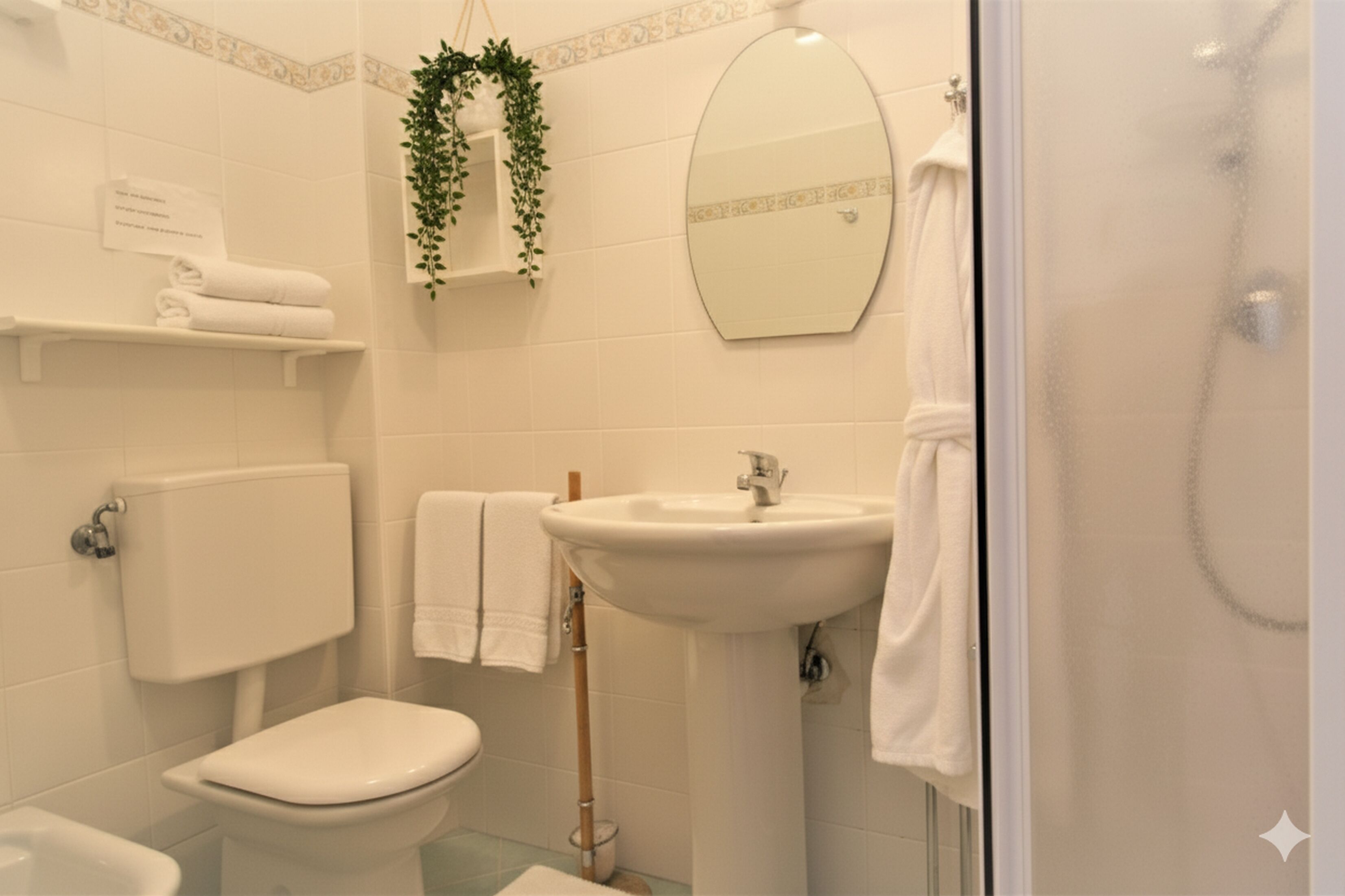 Une salle de bain avec des toilettes, un lavabo et une douche. Il y a des serviettes et un miroir au mur.