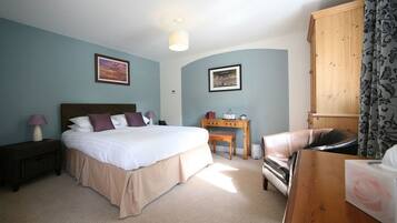 A bedroom with a bed, bedside table, lamp, desk, chair, and wardrobe.
