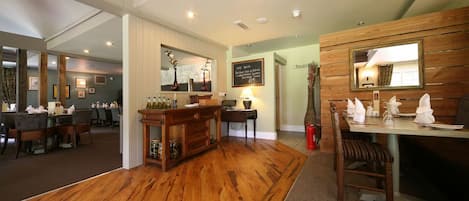 A restaurant with wooden flooring, a bar area, and a dining section with tables and chairs.