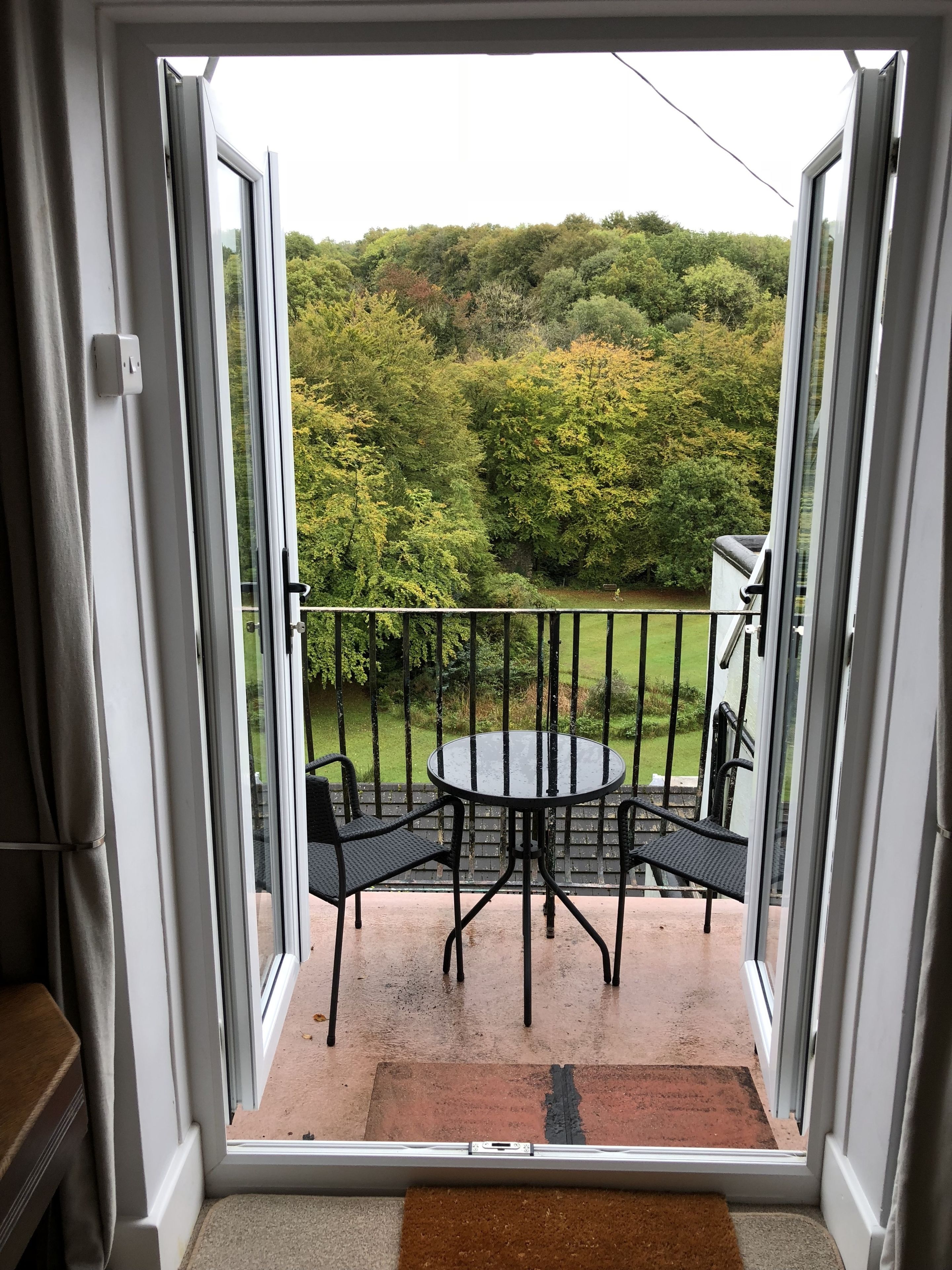 A balcony with a glass door, a round table, and two chairs.