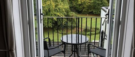 A balcony with a glass door, a round table, and two chairs.