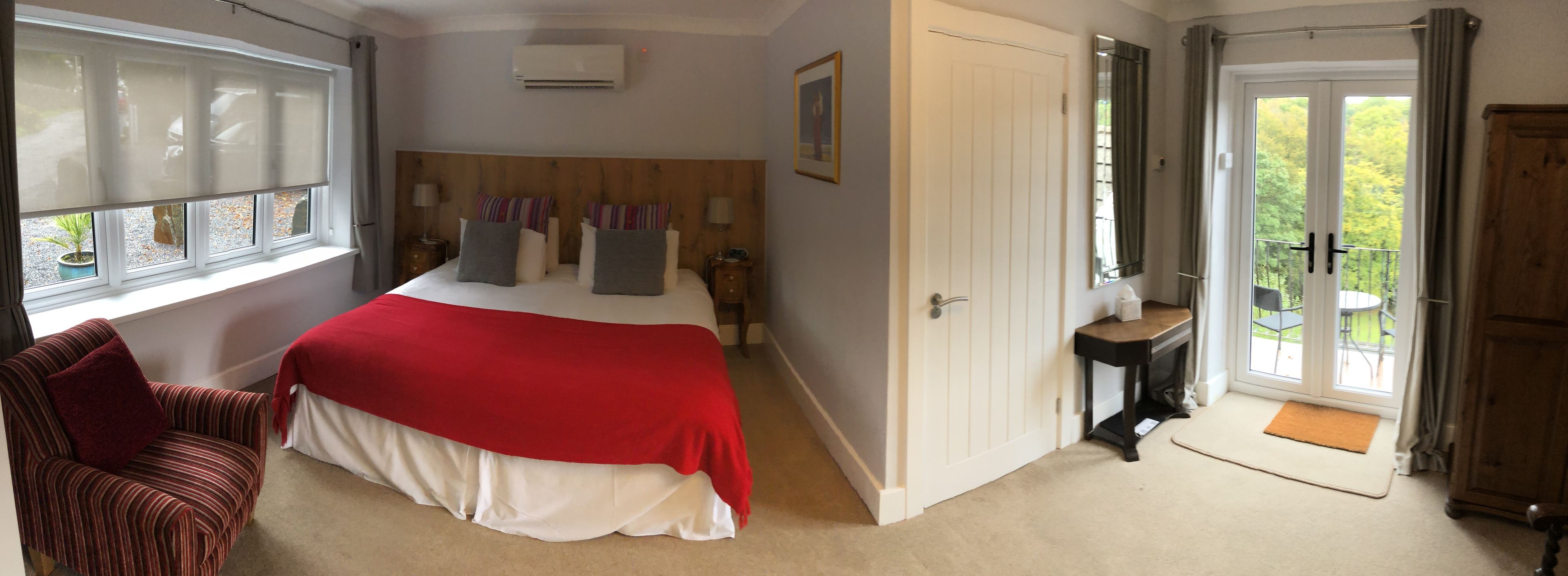 A bedroom with a bed, a chair, a door leading to a balcony, and an air conditioning unit.