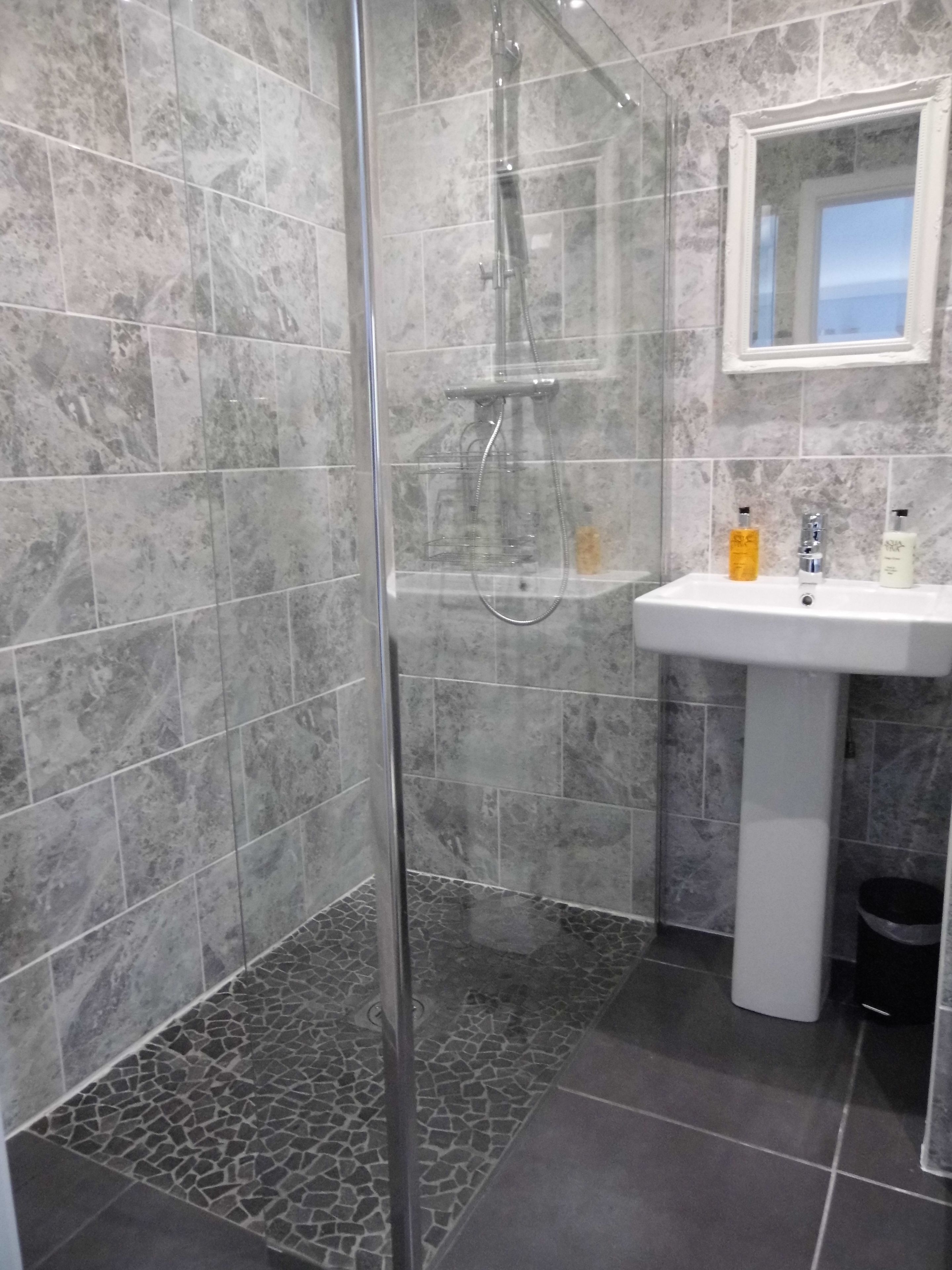 Un baño con ducha, lavamanos y espejo.