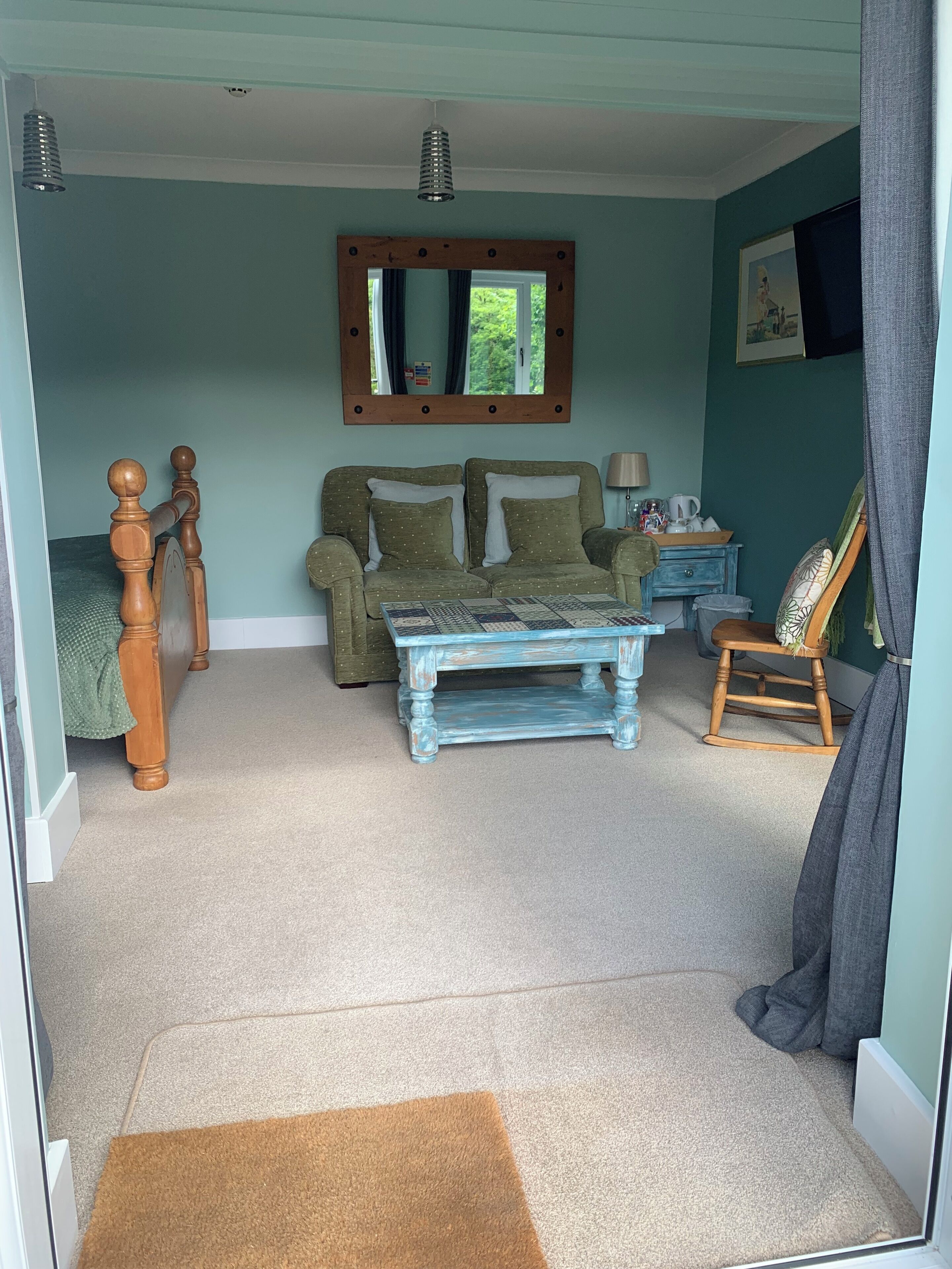 Una habitación acogedora con una cama de madera, una mesita de café azul, un sofá y un sillón mecededor.
