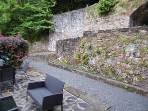 A stone wall with a small archway, a gravel path, and outdoor seating with chairs. - The Mill at Glynhir (Ammanford)