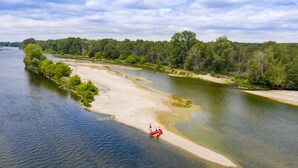 Een rivier met een zandige oever en weelderige begroeiing aan de overkant.