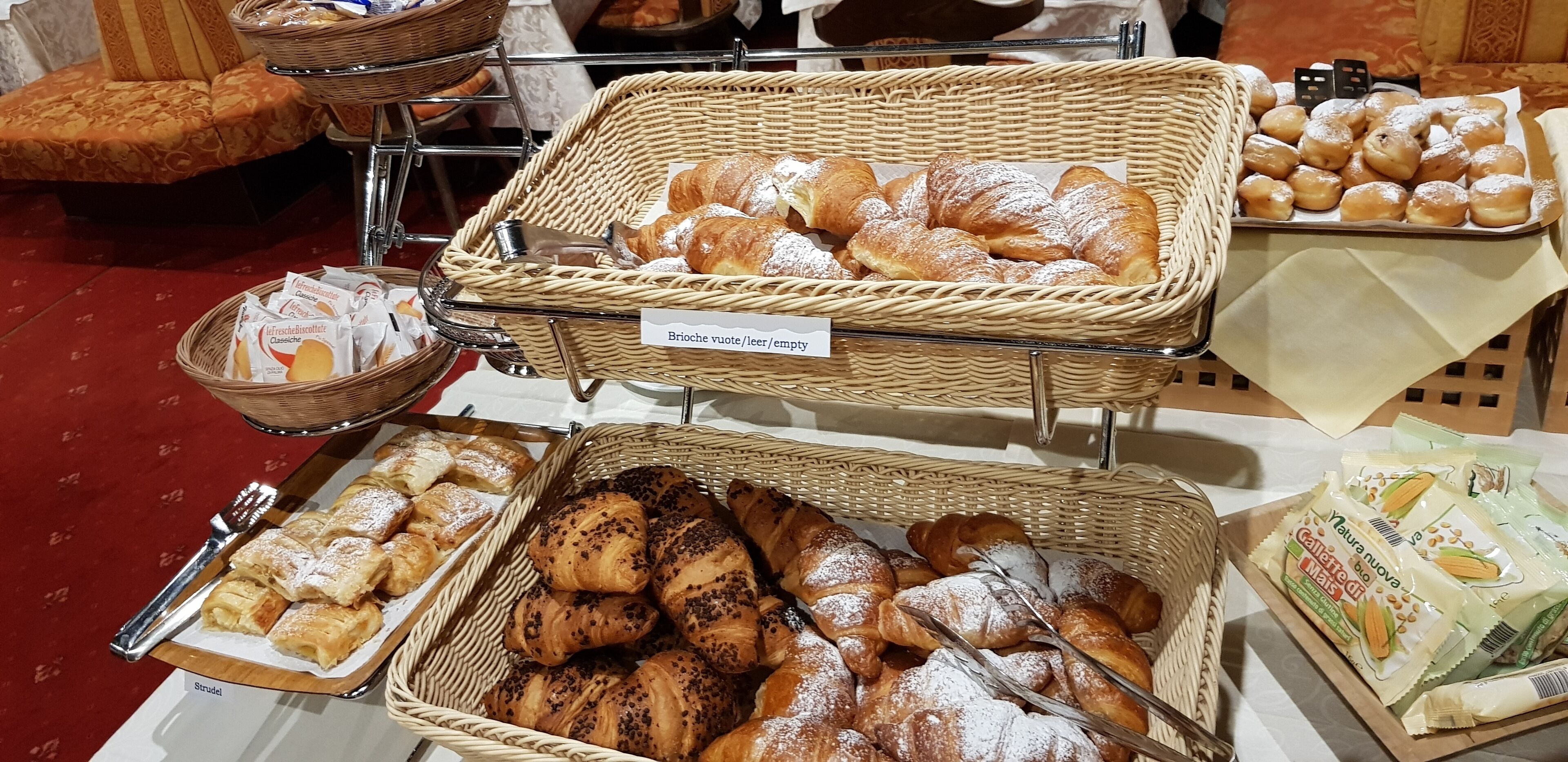 A buffet with various pastries and bread, including brioche, strudel, and croissants.