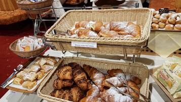 A buffet with various pastries and bread, including brioche, strudel, and croissants.