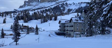 A snow-covered mountain with a ski resort building, including a ski lift and a chairlift.