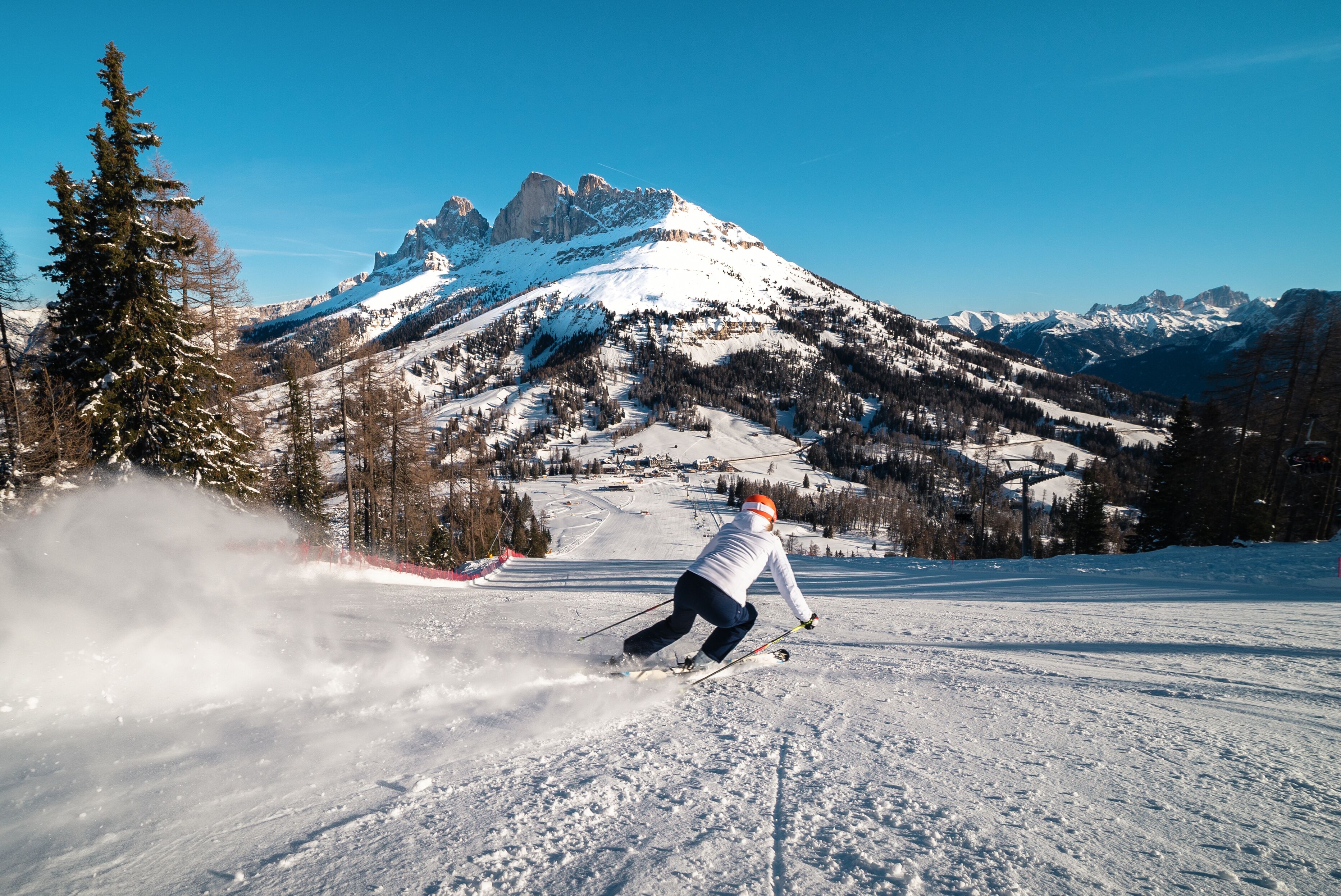 A skier on a snowy slope with a mountain backdrop.