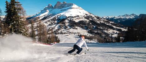 A skier on a snowy slope with a mountain backdrop.