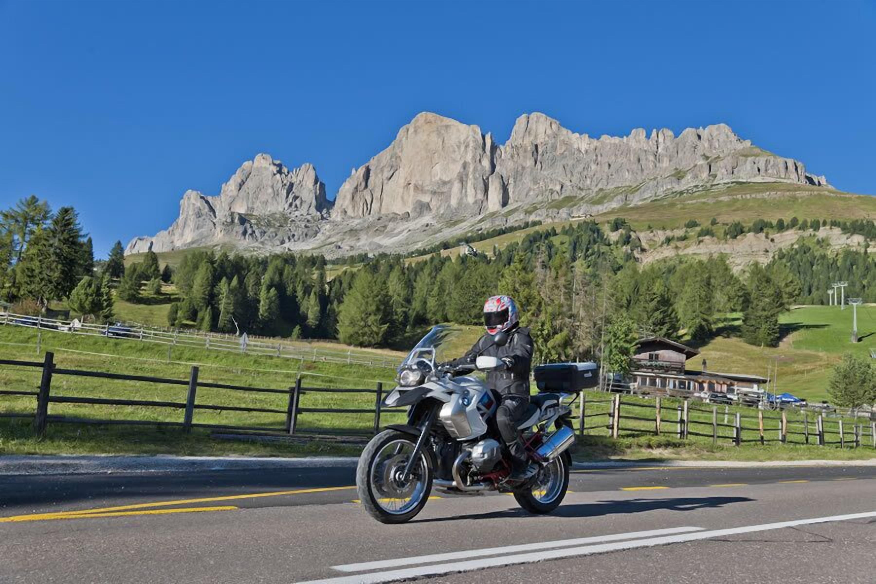 A motorcyclist riding on a road with a mountainous backdrop.