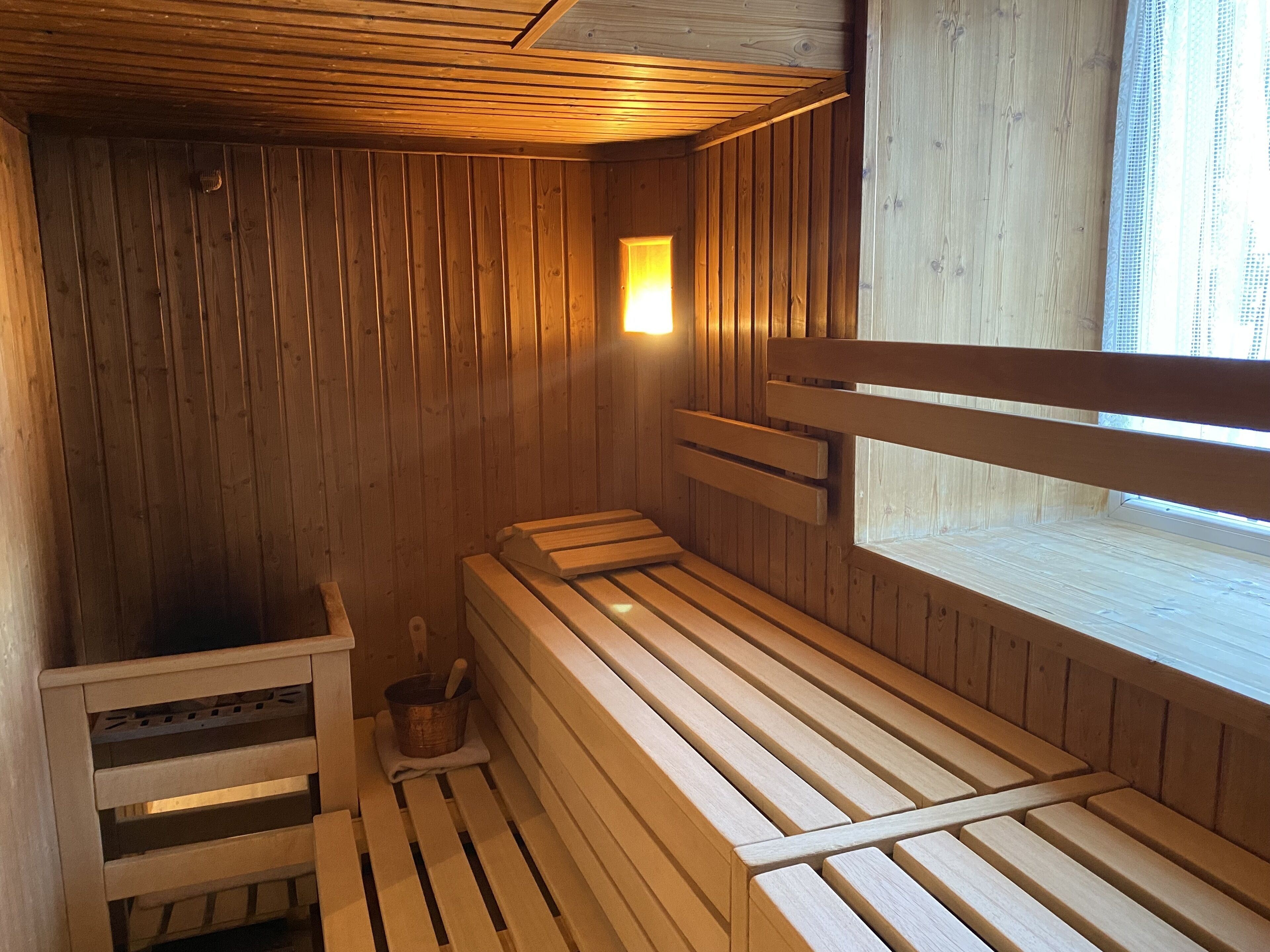 Un sauna en bois, doté de bancs et d’un petit seau pour verser de l’eau.