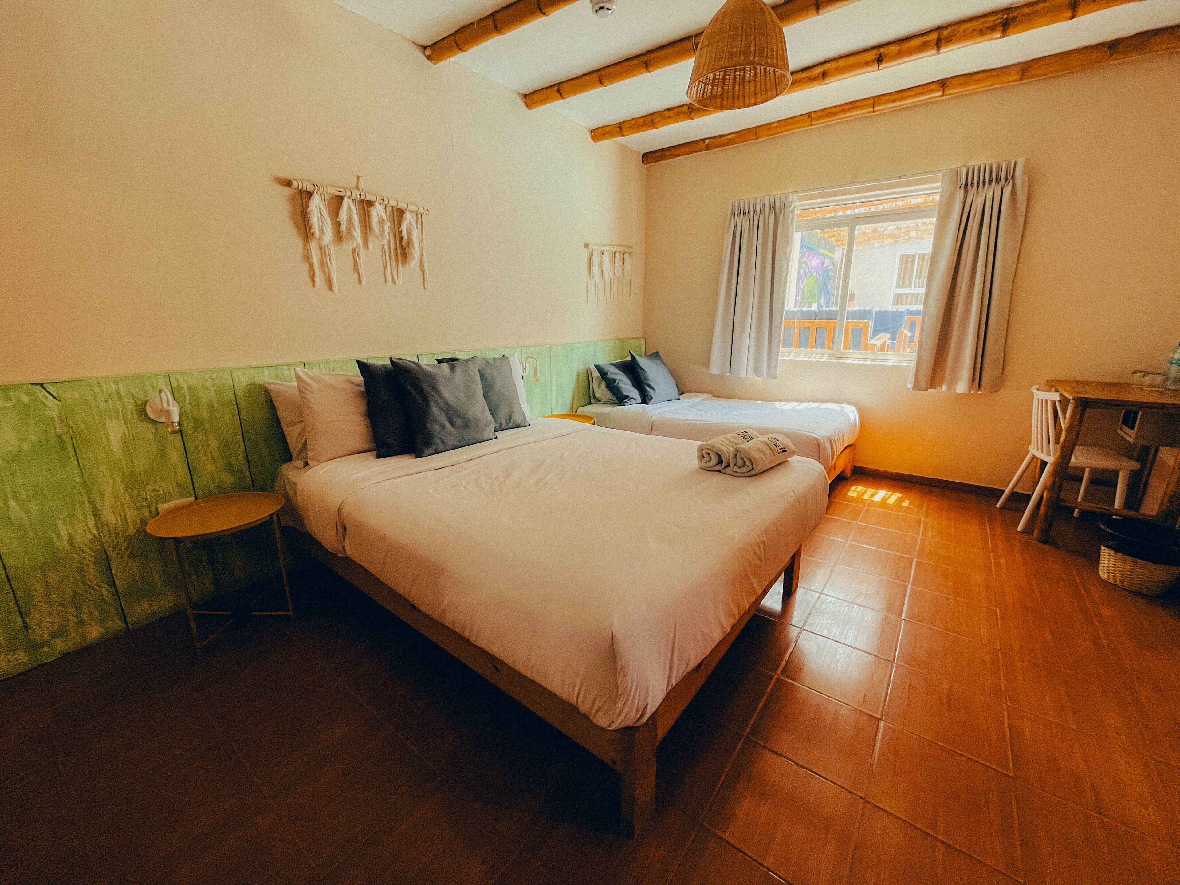 Quarto com duas camas, uma mesinha e uma cadeira.