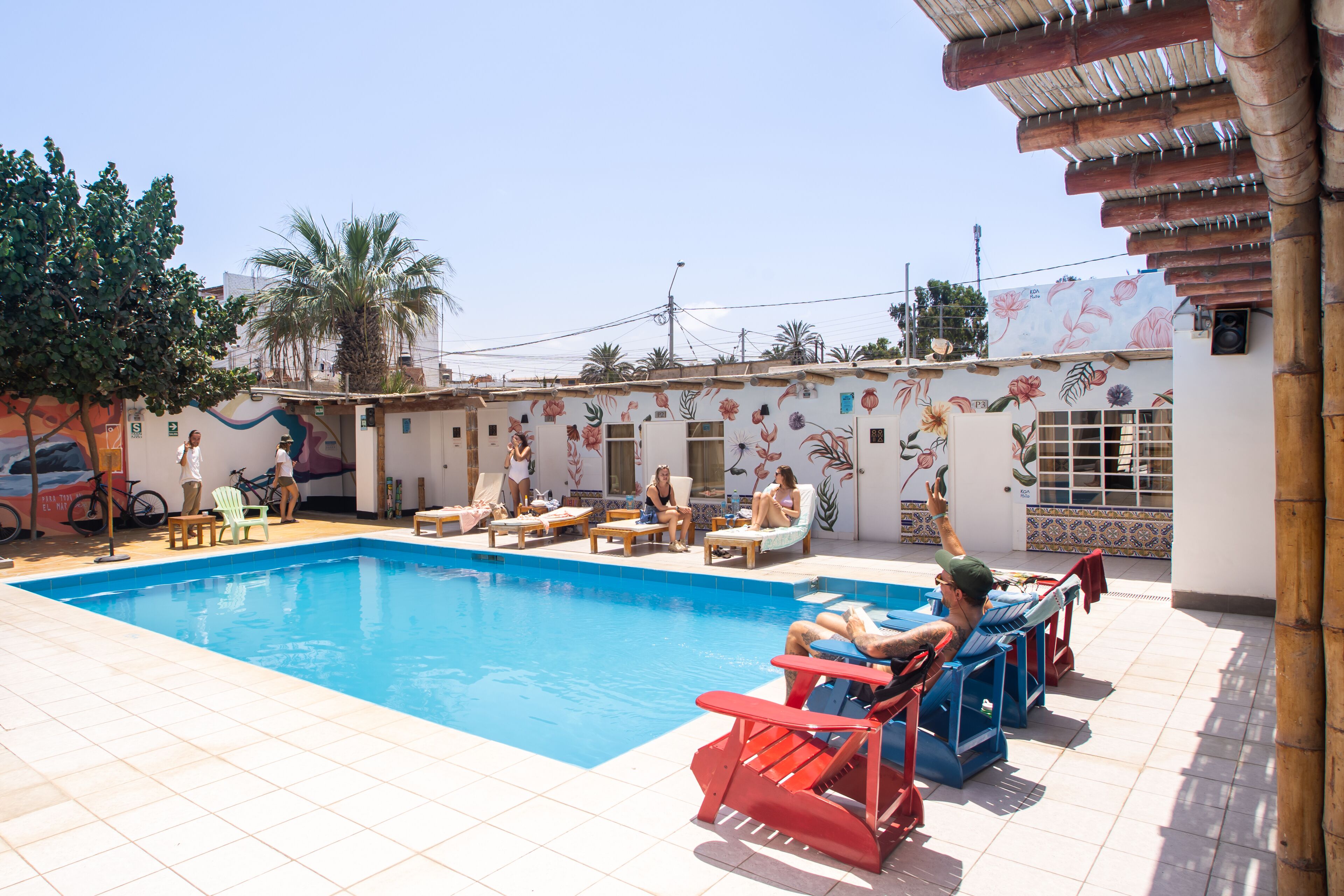 A swimming pool area with lounge chairs and a mural on the wall.