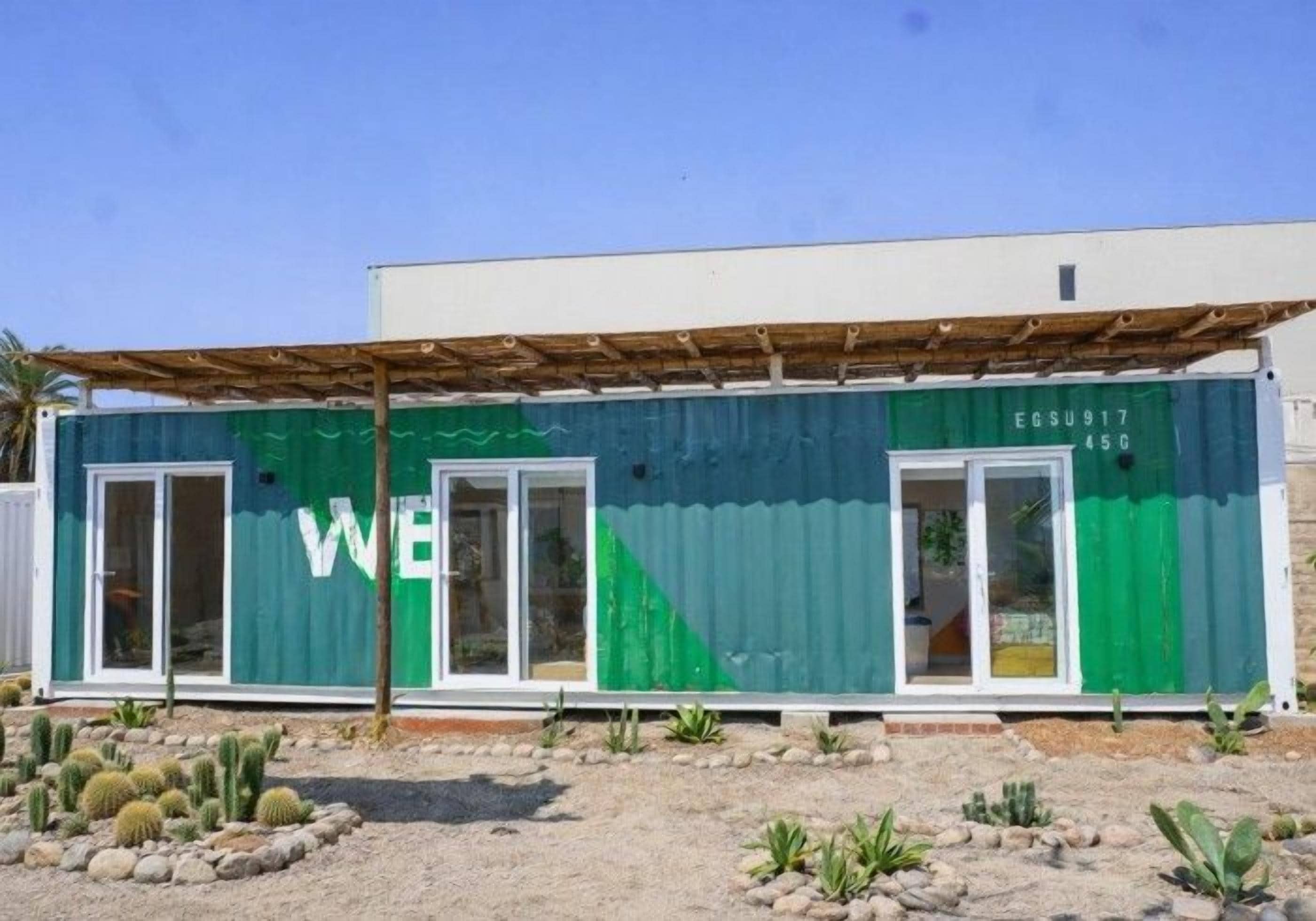 Un edificio verde y blanco con un letrero que dice 'WE', una puerta y una ventana.