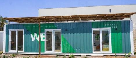 Un edificio verde y blanco con un letrero que dice 'WE', una puerta y una ventana.