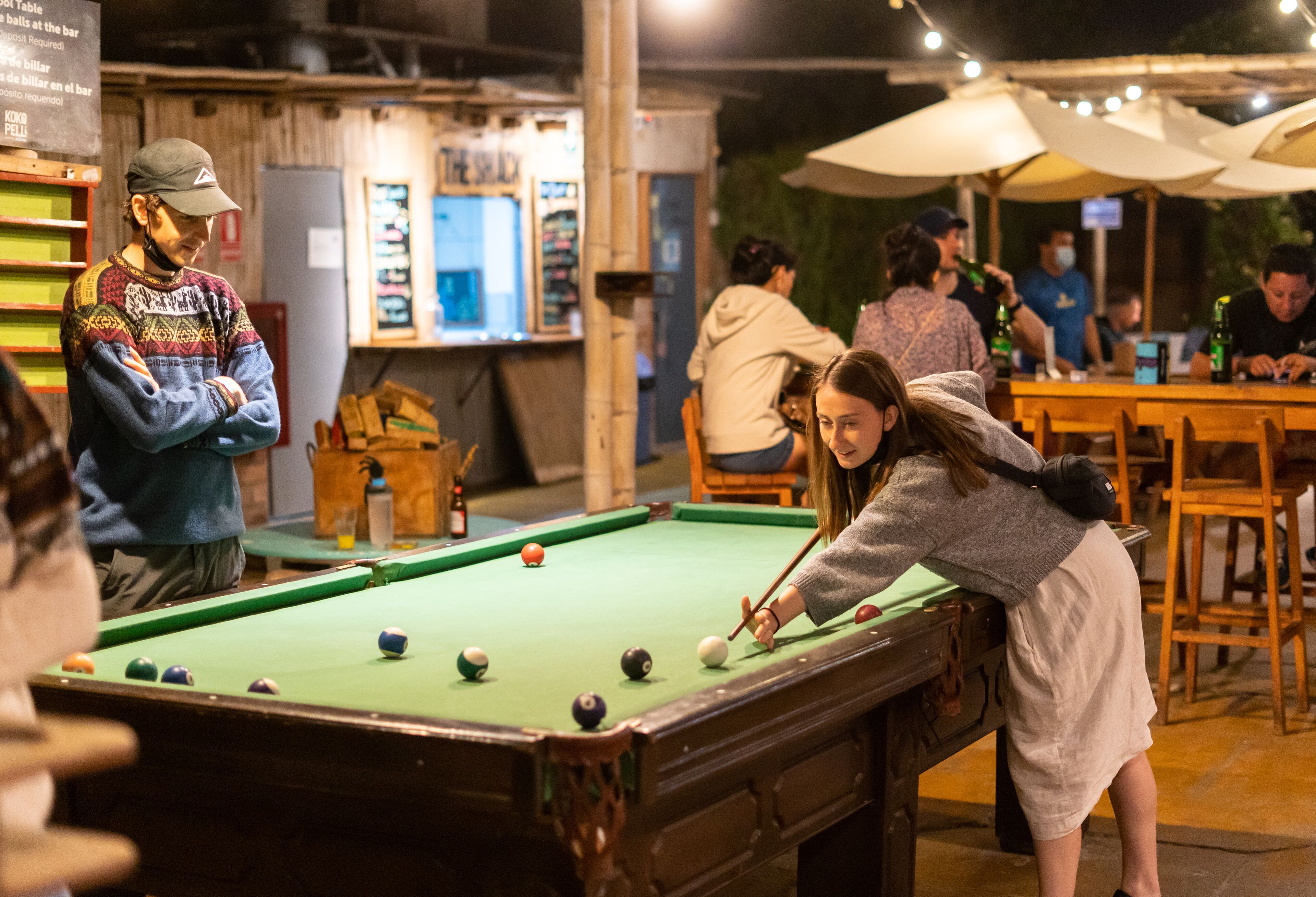 A pool table in a social setting with people around.