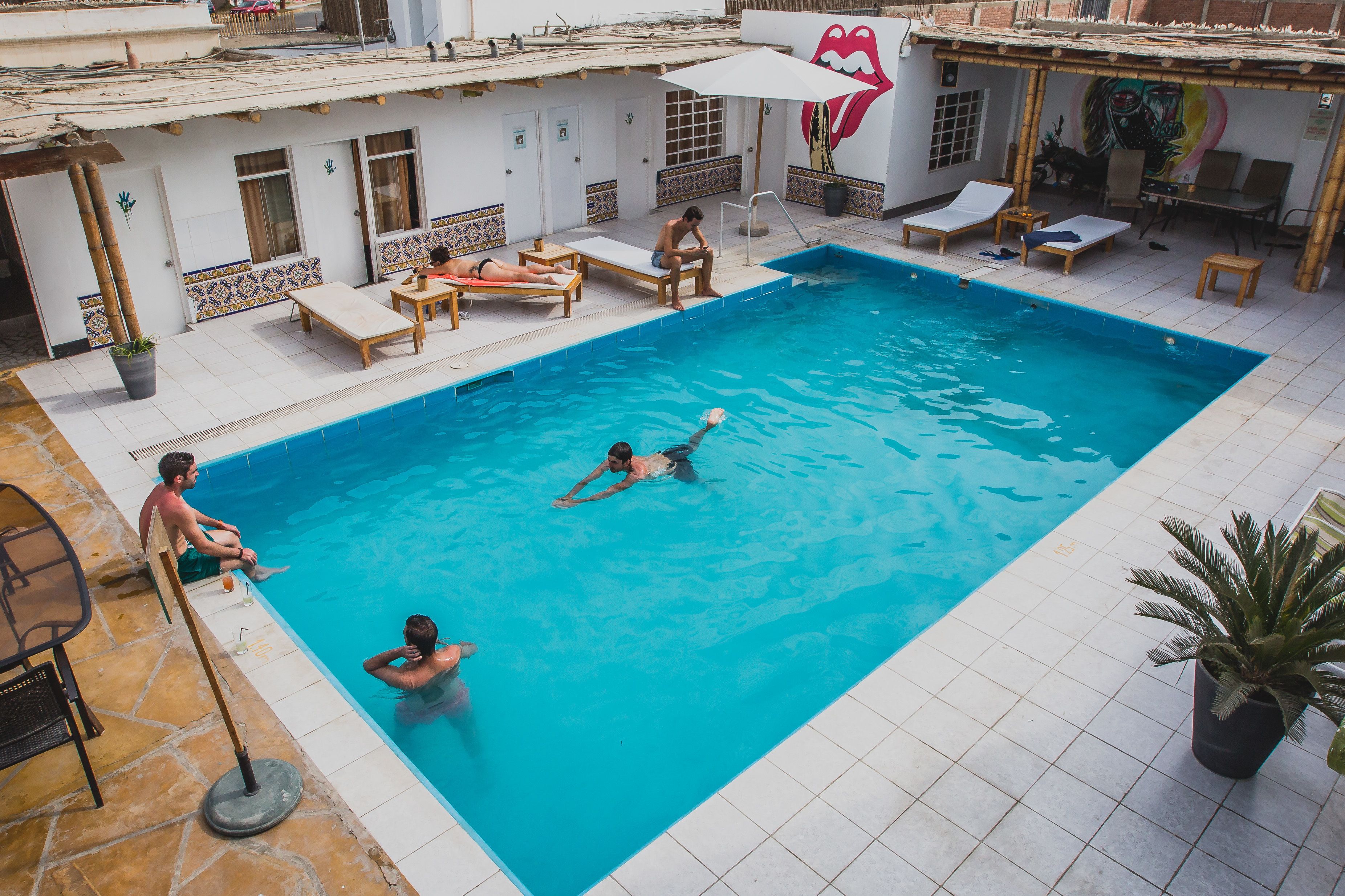 Una piscina con sillas de descanso y algunas personas.