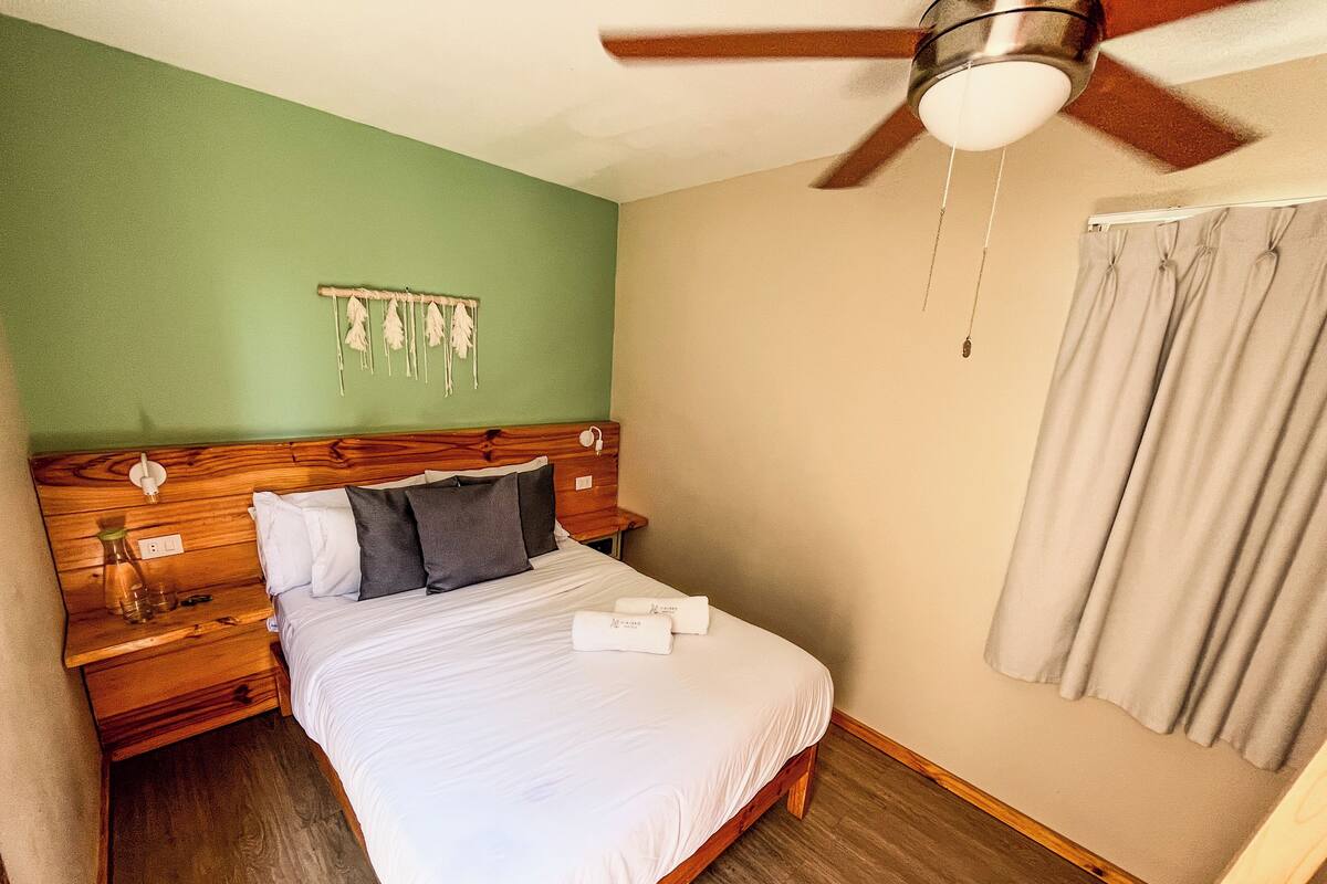 A neatly made bed with white linens, a wooden headboard, and a ceiling fan.