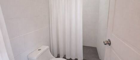 A small, clean bathroom with a toilet, a shower curtain, and tiled walls.