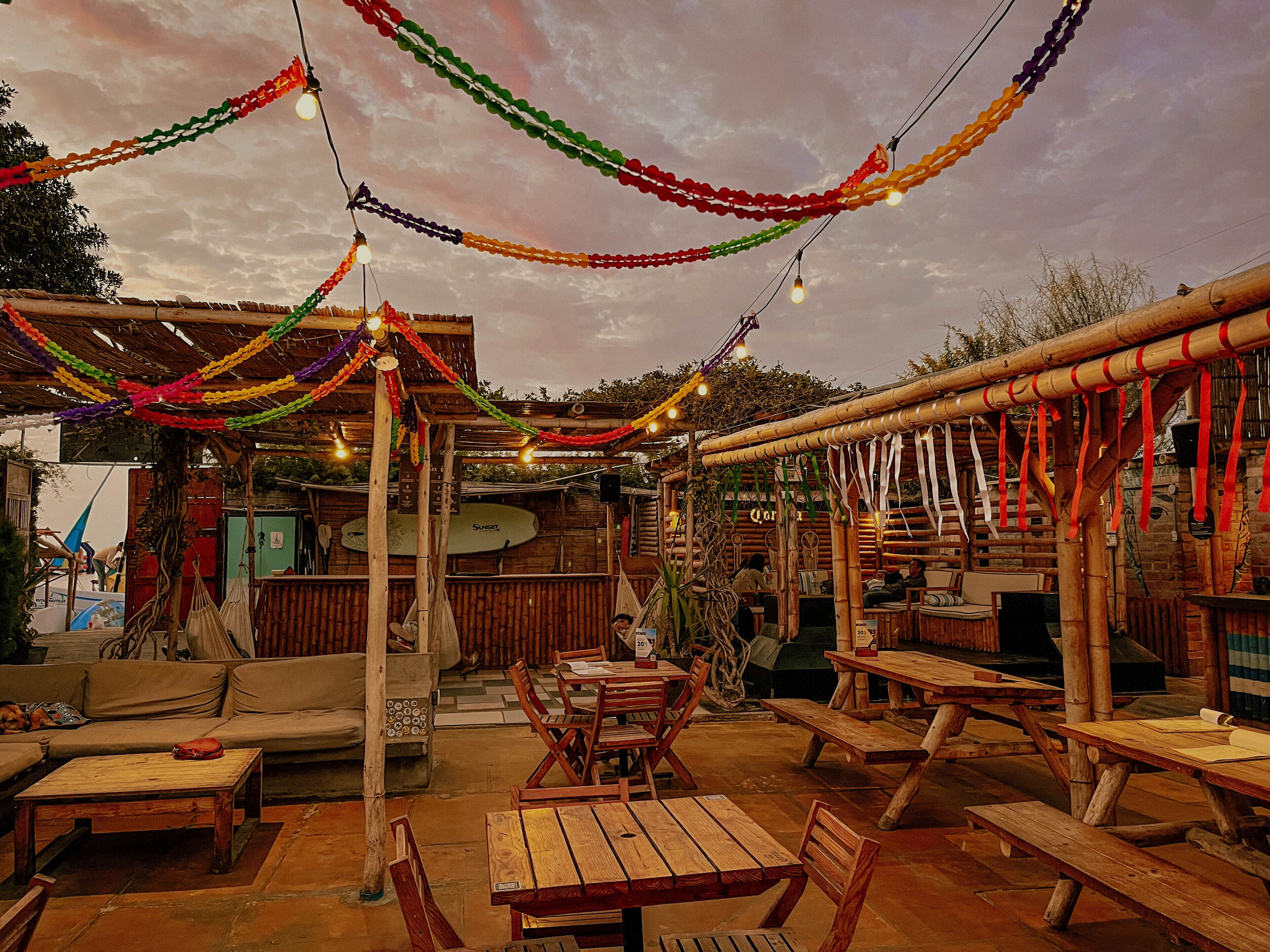 Un patio al aire libre con mobiliario de madera y luces colgantes.