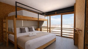 A bunk bed room with a city view, wooden walls, and a simple bed setup. - Viajero Paracas Hostel (Paracas)