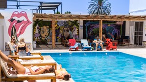 A poolside area with lounge chairs, a swimming pool, and colorful murals on the walls. - Viajero Paracas Hostel (Paracas)