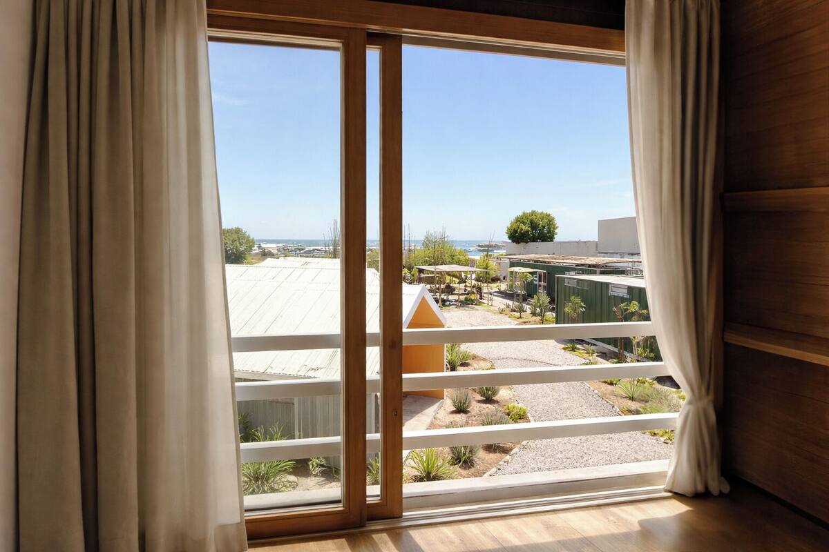 A balcony with a view of a residential area, including houses and a tree.